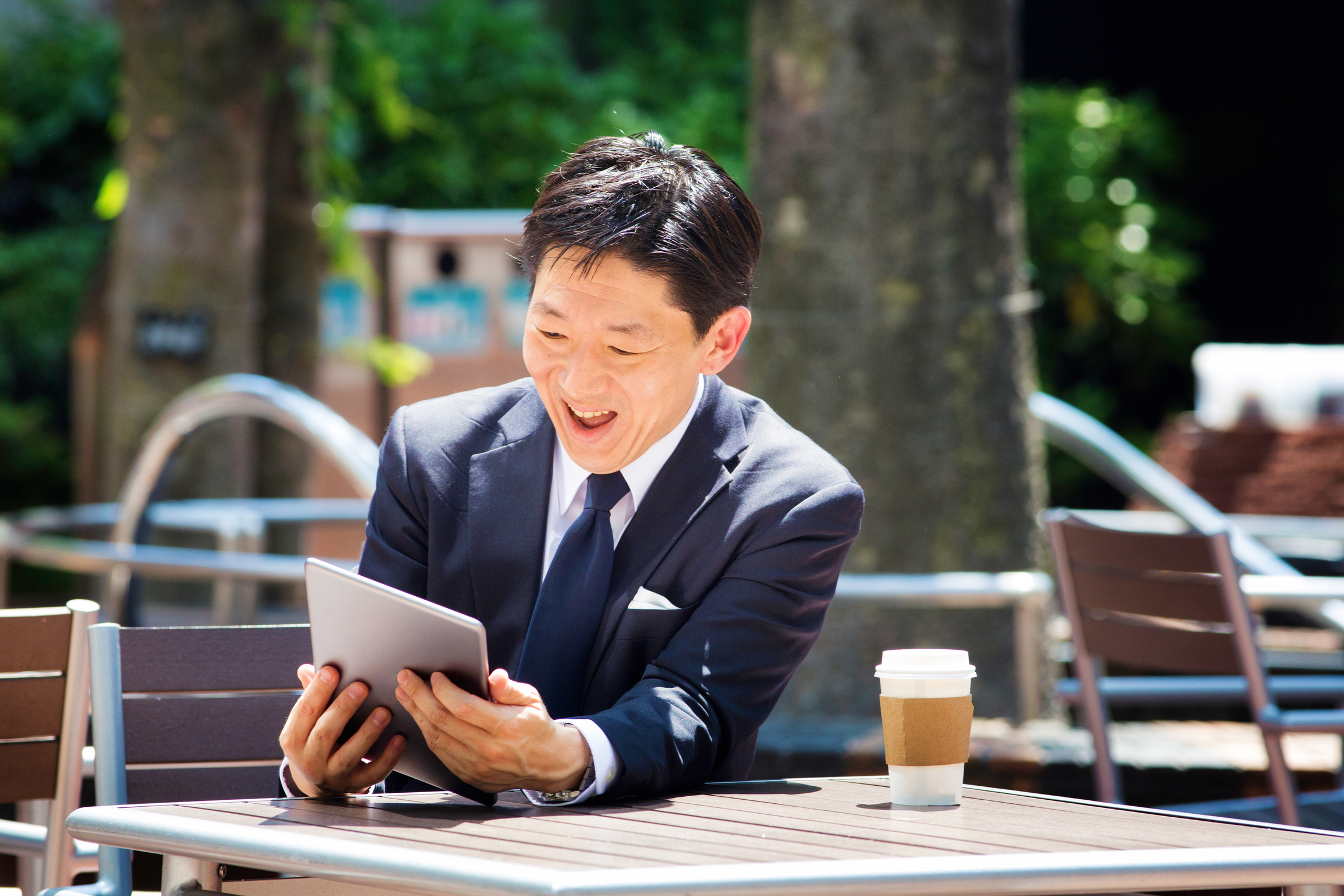 Japanese office worker smiles at tablet outdoors