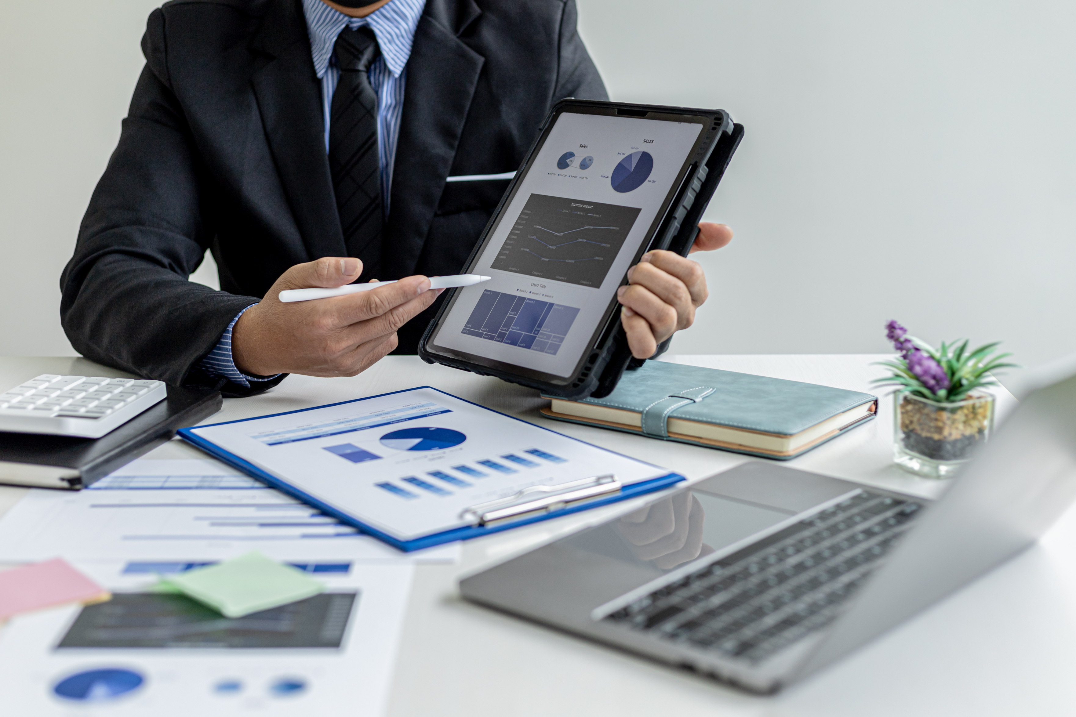 Businessman holding a tablet showing sales data of a salesperson, he is meeting with the sales manager to plan sales growth management, marketing plan to increase sales. Sales management concept.